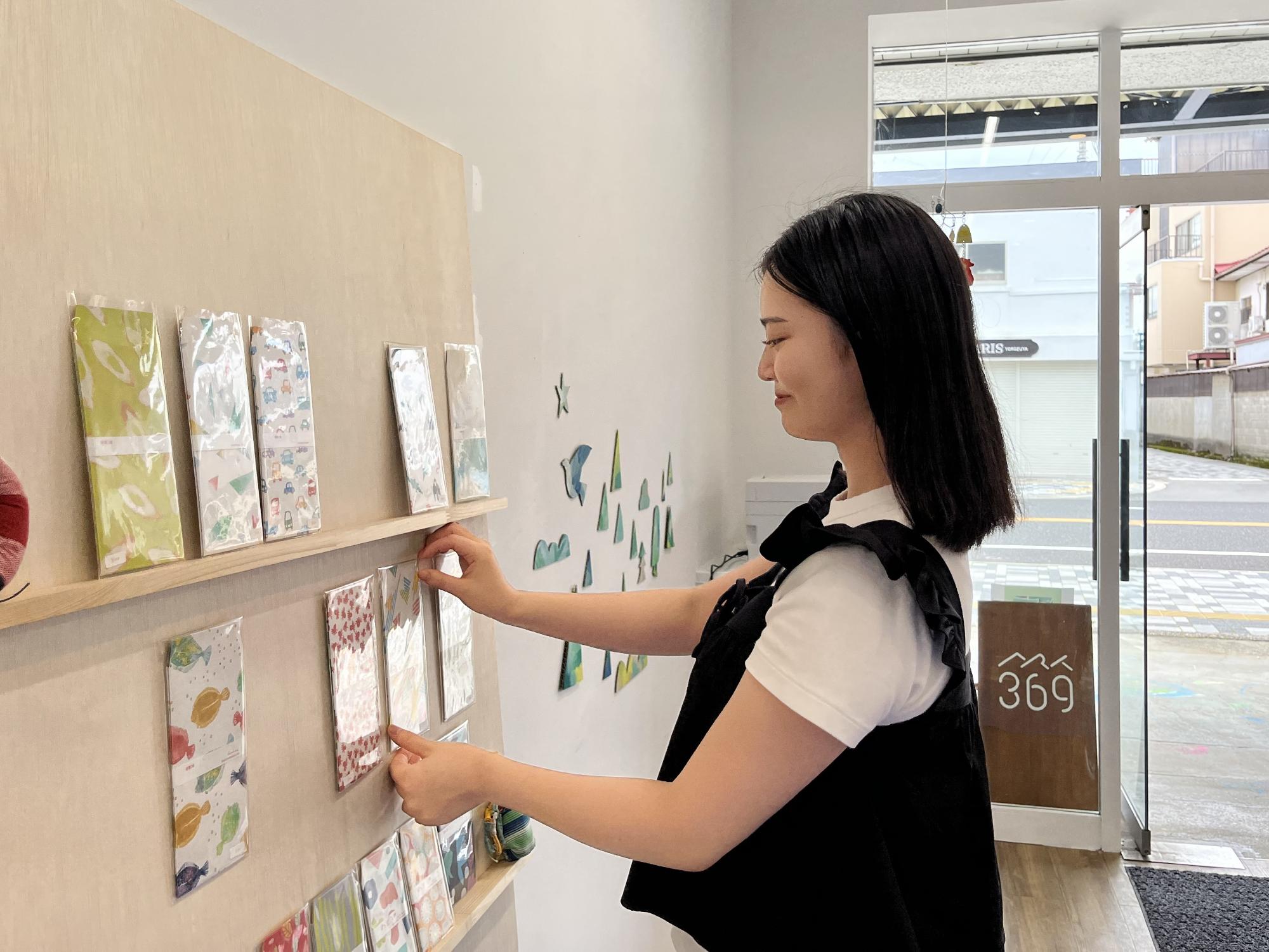 アートスペースにて封筒の作品を棚に並べる田浦隊員