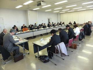 大勢の人が椅子に座って机を四角に囲んで討議している写真