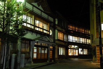 加登屋旅館の照明が窓から光って見える夜の外観の写真