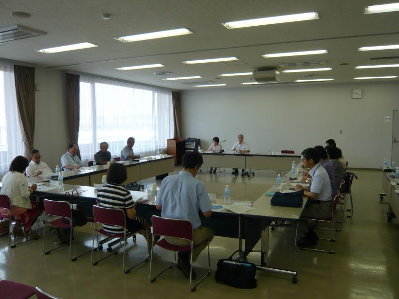 机を参加者が取り囲んで椅子に座っている、審議会の様子の写真