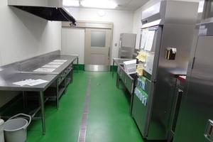 大きめの冷蔵庫や作業台が置かれているキッチンの写真