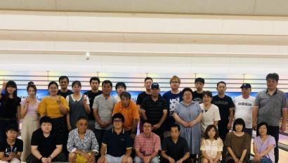 明るい照明が灯る室内で横3列に並んだ私服姿の施設職員たちの写真