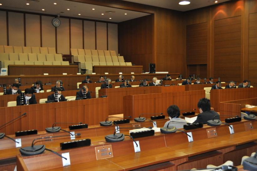 議会でたくさんの机が並んでいてスーツを着た男性たちが座っている写真