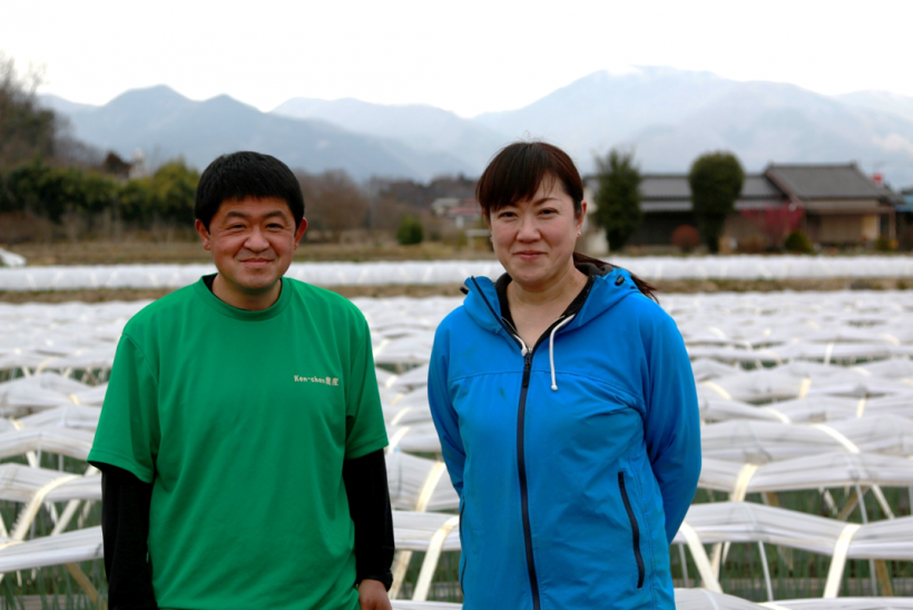 ネギ畑の前で奥さんと並んでいる藤田さんの写真