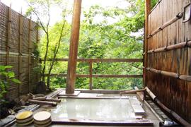 森林を背景とした渓雲閣の木の壁で囲われた露天風呂の写真