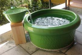 緑の容器から丸い緑の浴槽へ温泉のお湯が流れている写真
