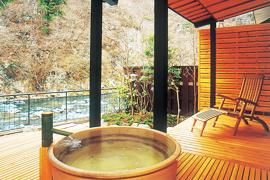 松楓楼松屋にある木製の露天風呂と端に川が流れている写真