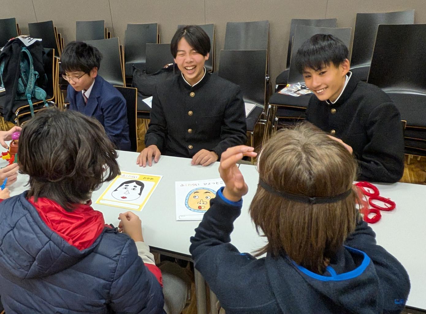 アウホフ校で行う文化紹介の様子。中学生がアウホフ校生徒に日本の遊びを紹介している。アウホフ校の生徒は福笑いを楽しんでいる様子。