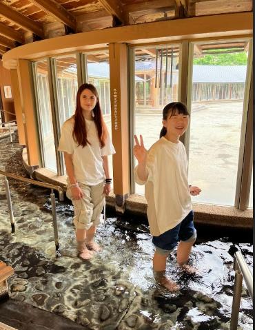中学生とホストパートナーがゆっぽの里で足湯を楽しんでいる。カメラに向かってポーズをしている。