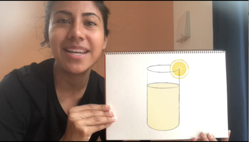 ALTのパオラ先生が、飲み物のイラストが描かれたスケッチブックをかざしているシーンのサムネイル画像。スケッチブックにはコップのフチにレモンの輪切りを挿したレモネードのイラストが描かれているのが確認できる