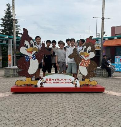 那須ハイランドパークの入り口で、笑顔で記念撮影をする男子生徒たちのグループ写真。