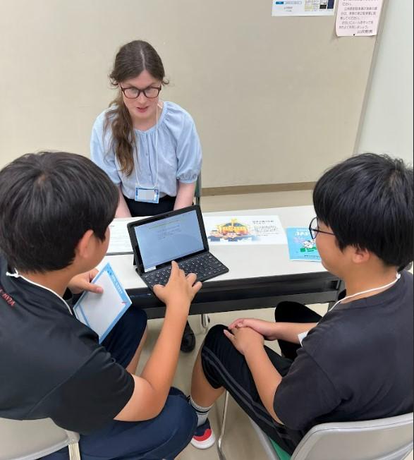 生徒2名がタブレットを使ってALTに日本の祭りについて説明している様子