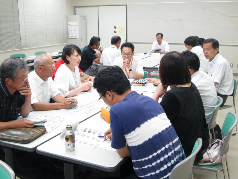 白いテーブルを囲み、グループになって会議を行う参加者たちの写真