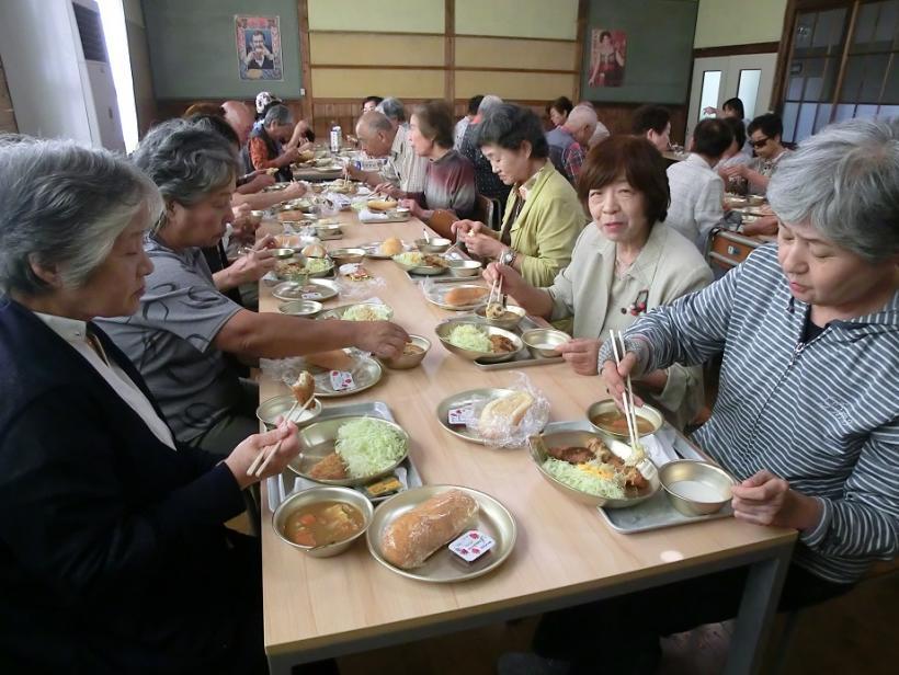 広いテーブルの上に料理が並べられて会食している写真