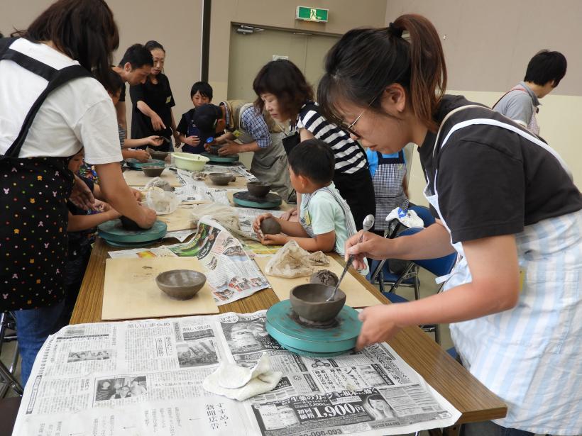 陶芸教室でお茶碗を作っている様子の親子の参加者たちの写真