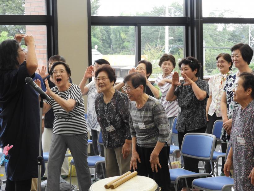 講師の先生の身振り手振りに合わせて手振りをしながら歌っている参加者の皆さんの写真