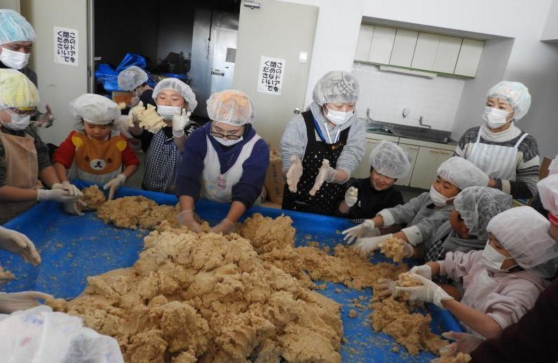 大豆と米麹を混ぜている様子の小学生たちの写真