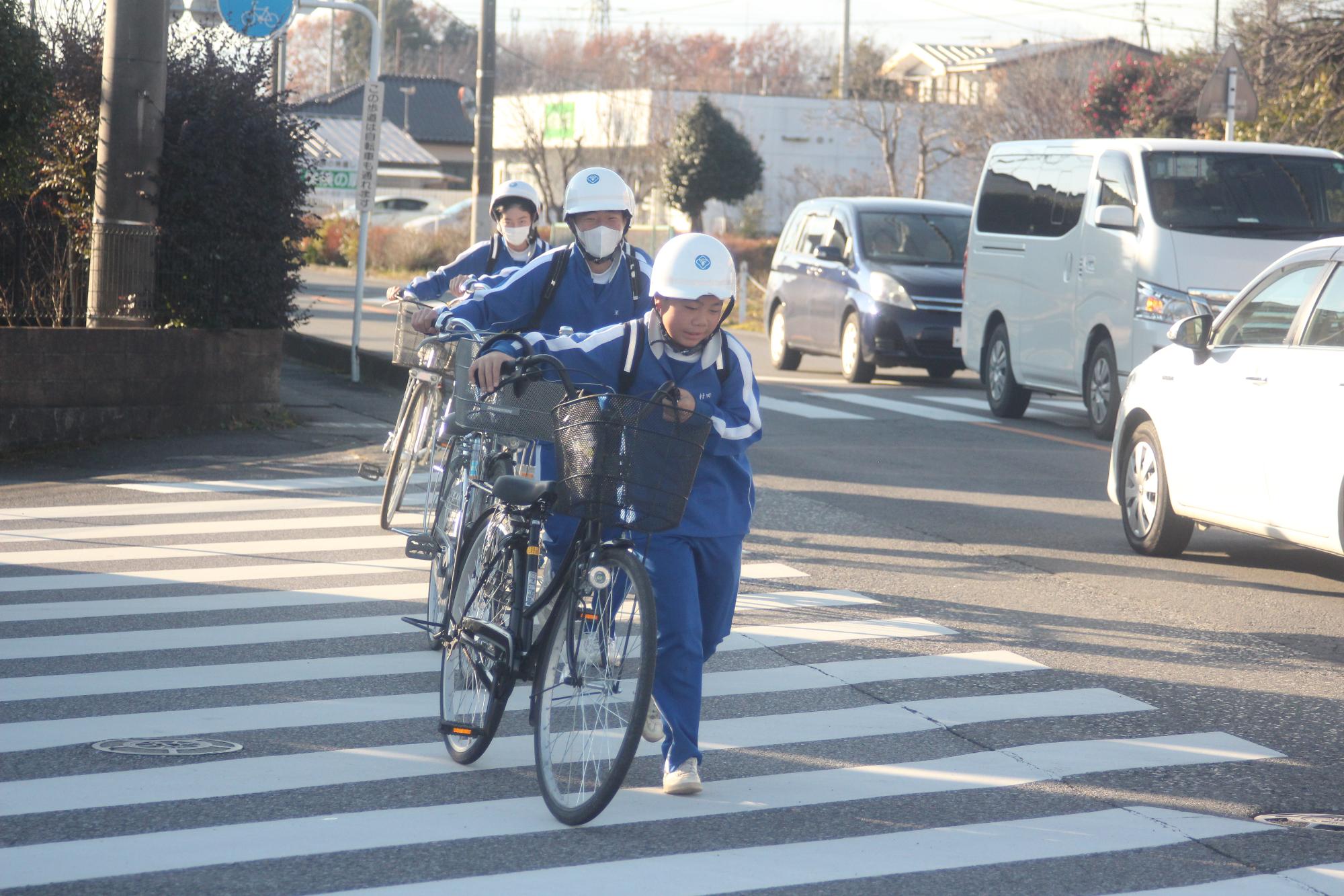 自転車を押して横断歩道を渡る生徒