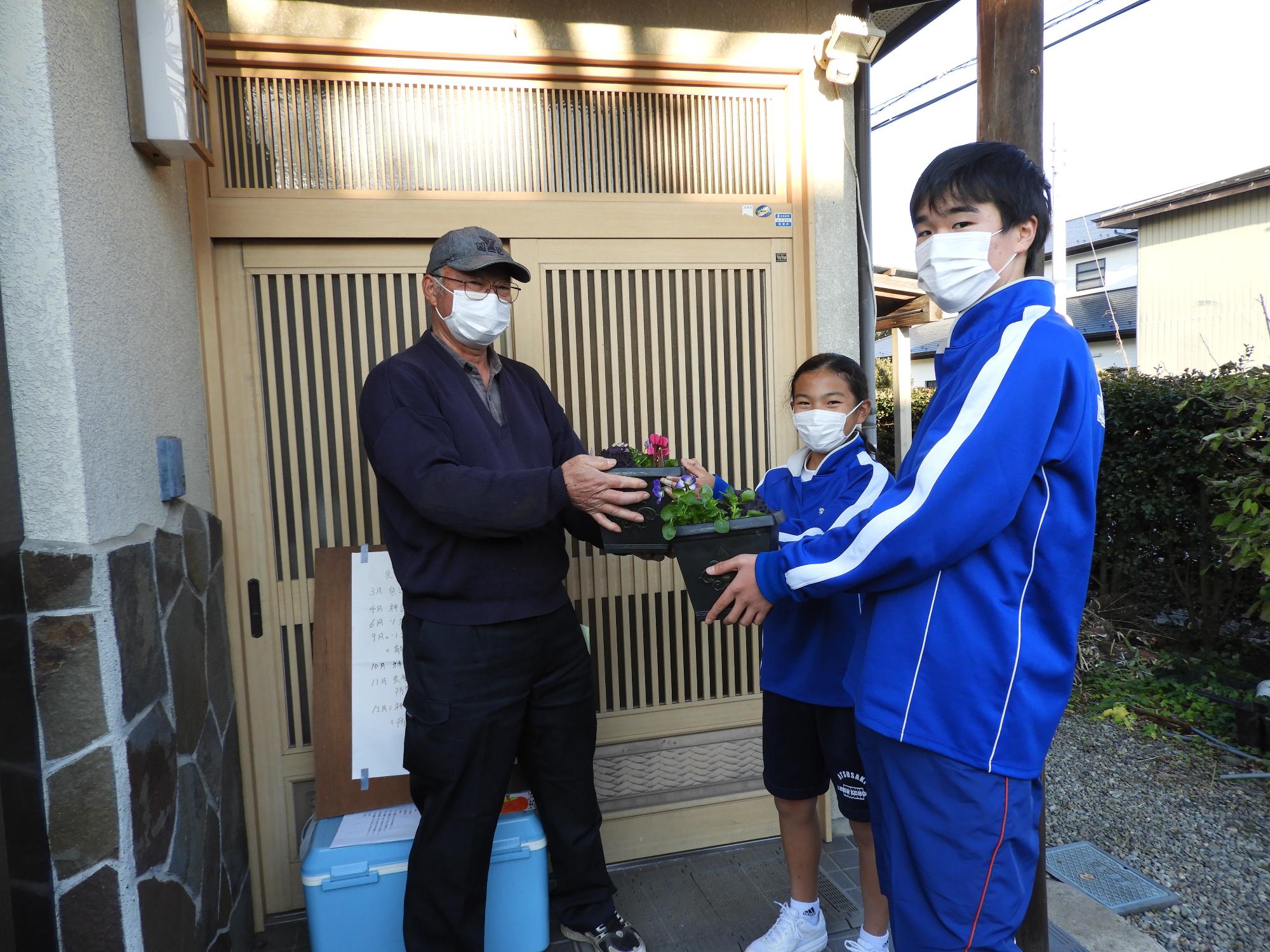 中学生が感謝の花を自治会長にプレゼントしている様子