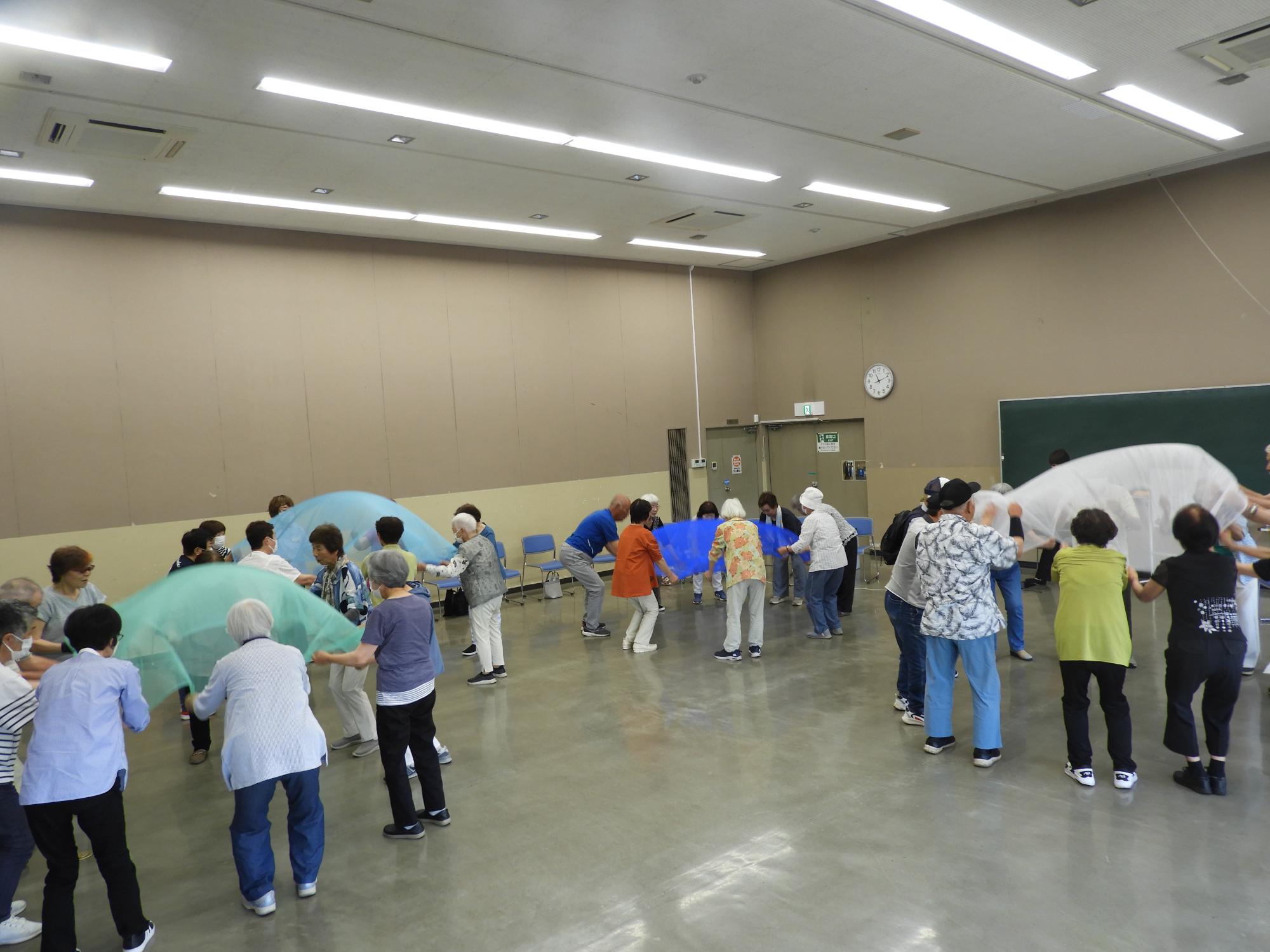 輪になってスカーフを持ち音楽に合わせて上下する様子