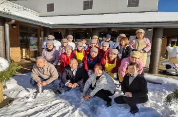 外でカメラに向かって笑顔で並ぶユニフォーム姿の施設スタッフの写真
