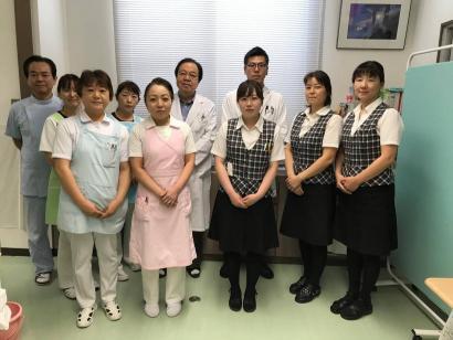 医療事務の服、事務用の制服を着て並んでいる男女の写真