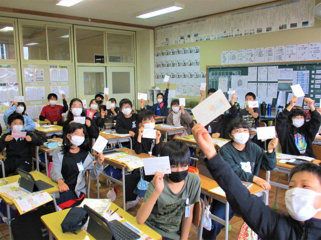 書いた手紙を嬉しそうにこちらに見せている児童たち