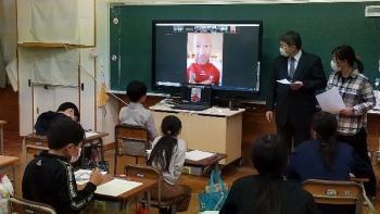 那須塩原市立西小学校の教室でおこなわれたオンライン交流会において、電子黒板に映し出されたグリチュ選手と会話する児童たちを後ろから撮影した写真