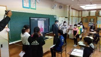 那須塩原市立西小学校の教室でおこなわれたオンライン交流会において、電子黒板に映し出されたグリチュ選手と会話する児童を左後ろから撮影した写真
