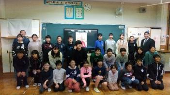 那須塩原市立西小学校の教室でおこなわれたオンライン交流会において、電子黒板に映し出されたグリチュ選手を囲んで記念撮影をする児童たちの写真