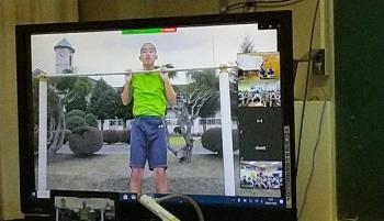 市立東那須野中学校の教室でおこなわれたオンライン交流会において、中学校の校庭にある鉄棒で運動する生徒の動画を映し出した電子黒板の写真