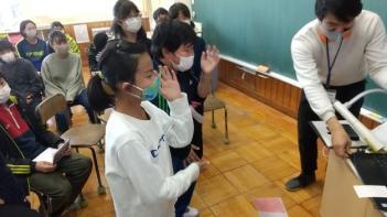 市立埼玉小学校の教室でおこなわれたオンライン交流会において、通信機材である電子黒板の前で日本の文化を紹介する児童たちの写真