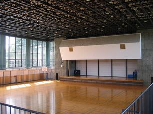 体育館（アリーナ）の内装の写真。アリーナの奥にはステージの併設も確認できる