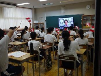 市立東那須野中学校の教室でおこなわれたオンライン交流会において、橋本オリパラ担当大臣が映し出された教卓の電子黒板を自分の席から見る生徒たちの写真