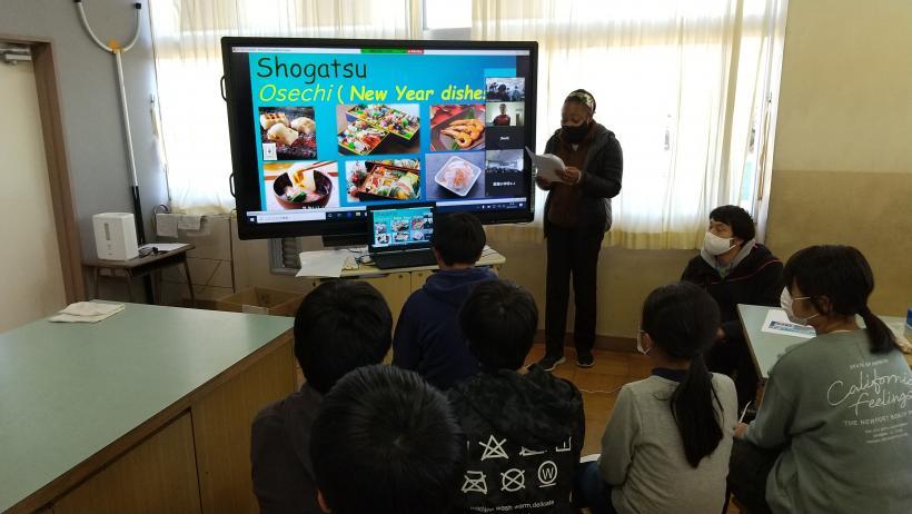 市立東原小学校の教室でおこなわれたオンライン交流会において、マルツィンケ選手に日本の正月を紹介する児童たちの写真。電子黒板にはおせち料理などの正月料理の写真が映し出されている。