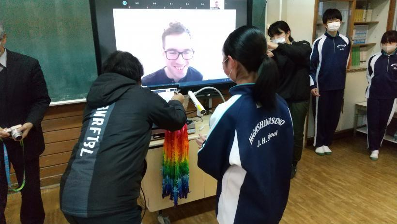 市立東那須野中学校でのオンライン交流会にて、教室に置かれた電子黒板を介してオネア選手に千羽鶴をプレゼントする生徒たちの写真