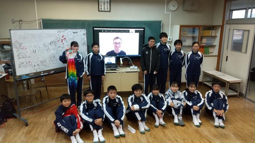 市立東那須野中学校でのオンライン交流会にて、教室の電子黒板に映し出されているオネア選手とともに記念撮影をする生徒たちの写真