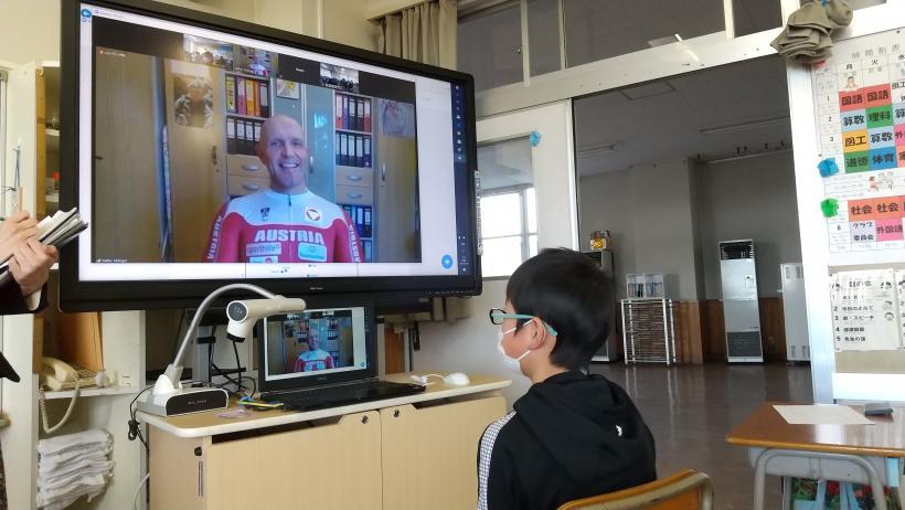 市立東小学校でのオンライン交流会にて、教室の廊下側隅に置かれた電子黒板のすぐ前に椅子を置いてアブリンガー選手と会話をする児童の写真