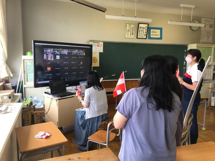 青木小学校の教室で窓側の隅に置かれた電子黒板やパソコンなどの機材を使い、オネア選手とのオンライン交流会に参加する児童たちの写真