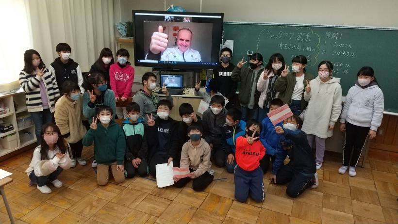 市立埼玉小学校の教室でおこなわれたオンライン交流会において、電子黒板に映し出されているシャッタウアー選手とともに記念撮影をする児童たちの写真