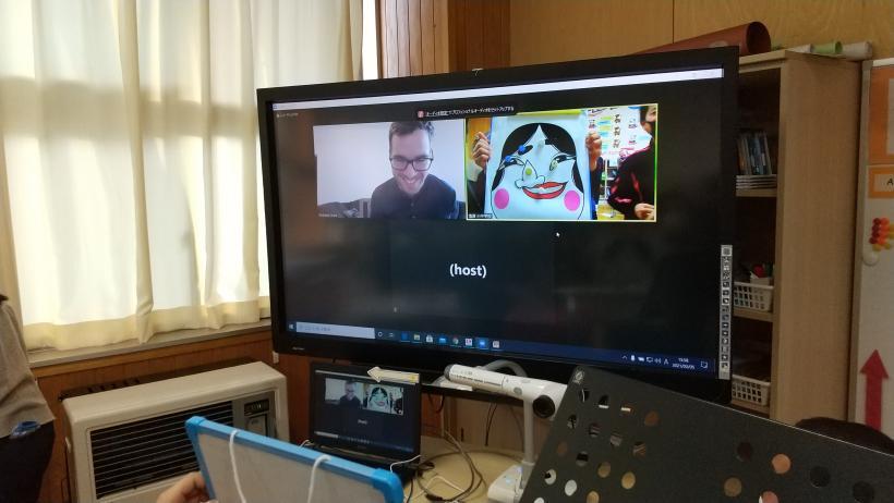 市立塩原小中学校の教室でおこなわれたオンライン交流会にて、福笑いを楽しんだオネア選手と出来上がった福笑いの顔が映し出されている電子黒板の写真