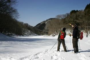 雪原の上で2人の参加者が近くの山を眺めている、塩原の冬の自然の風景の写真