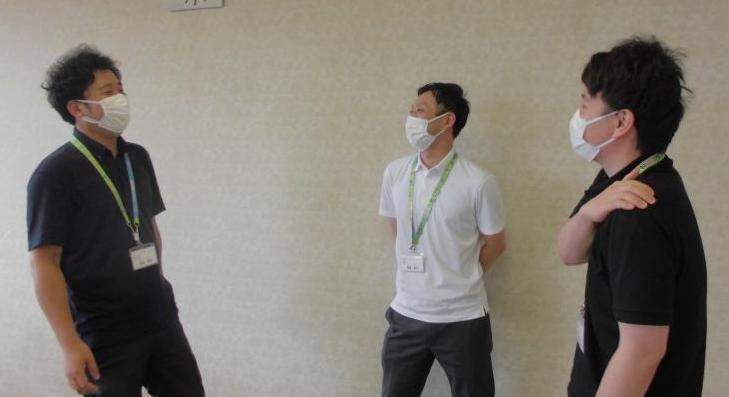渡邉技師を含む3人の男性がマスク着用と距離をとって談笑している写真